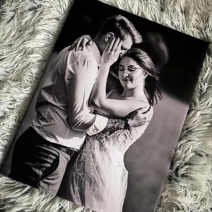 Czarno-biały fotoobraz przedstawiający zakochaną parę w objęciach na tle dywanu.