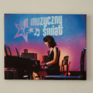 Fotoobraz przedstawiający kobietę grającą na pianinie podczas koncertu z napisem Muzyczny Świat w tle